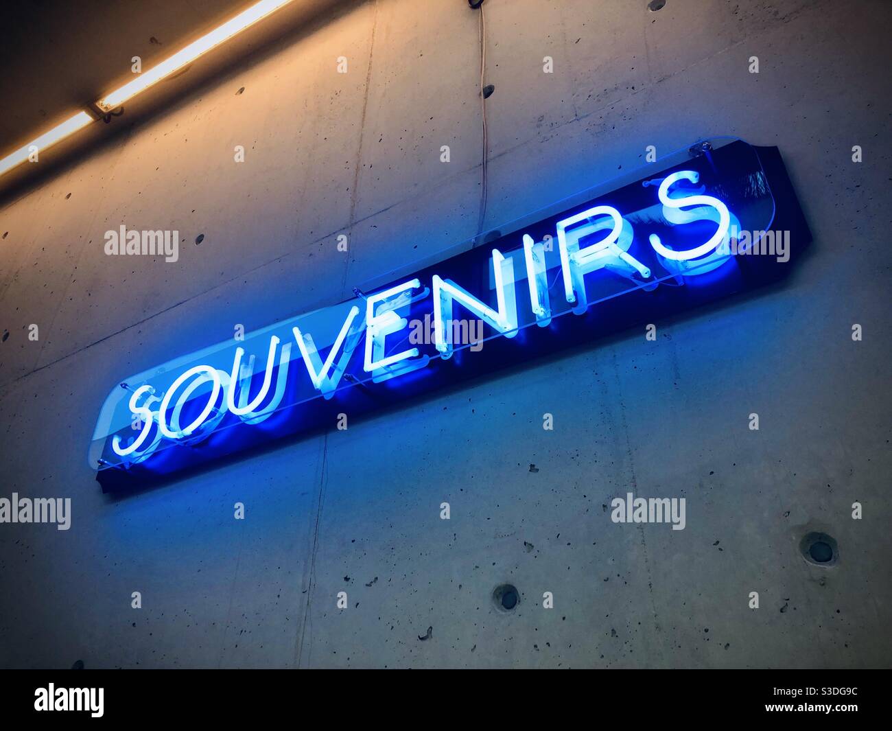 Neon light art showing the word souvenirs on a concrete wall Stock Photo