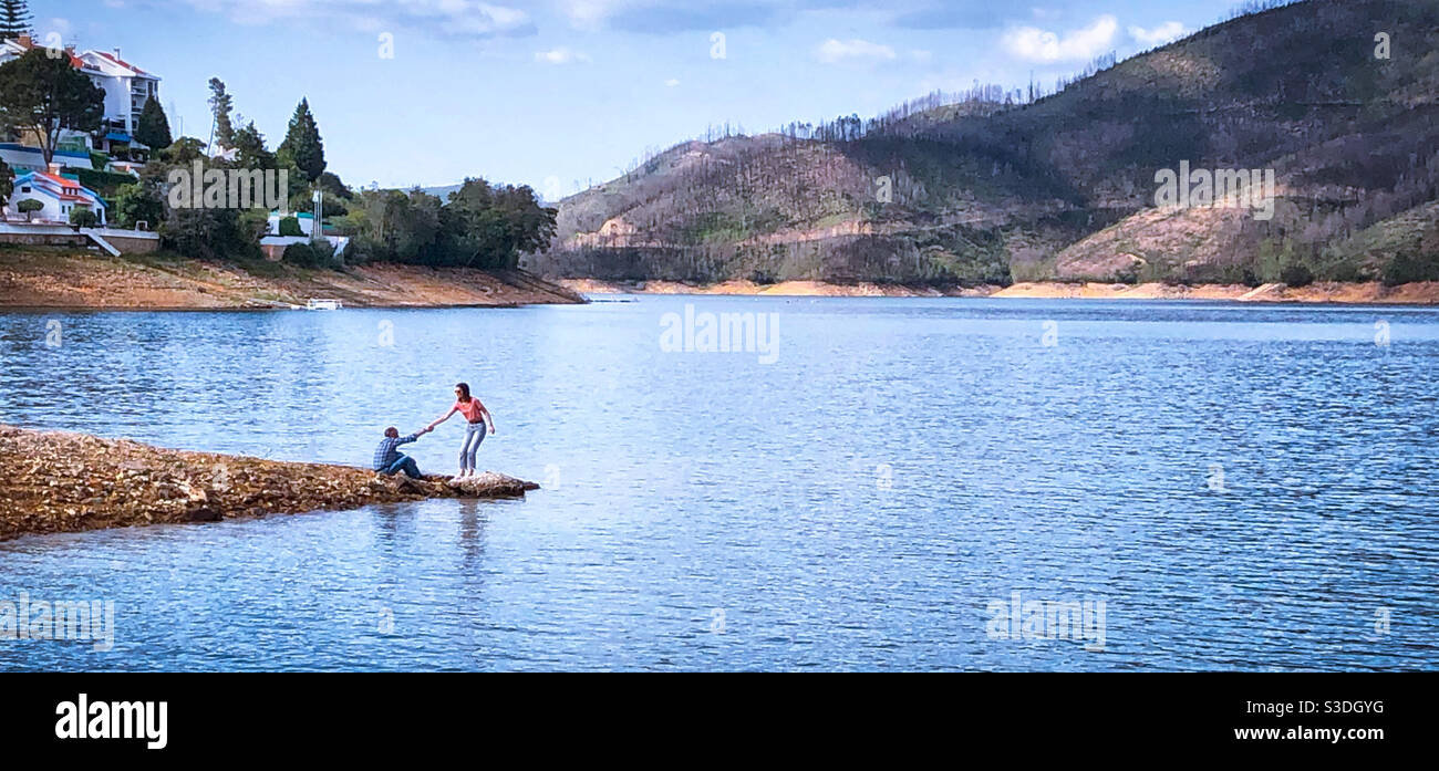 A helping hand: one person helps another up, next to Rio Zêzere in Central Portugal - Smartphone Captured Stock Image