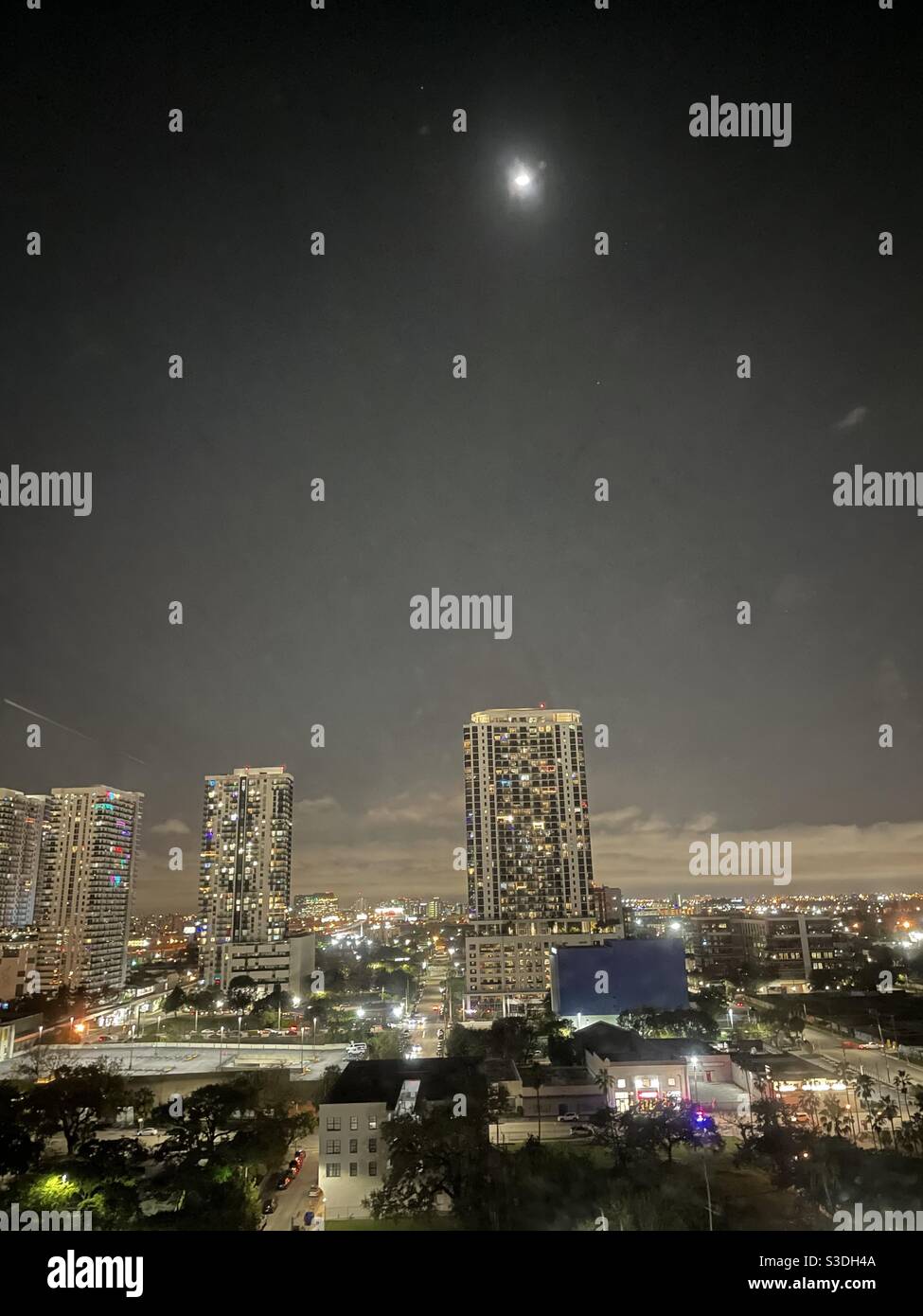 The moon over Miami, Florida, USA, facing west toward high-rise apartment buildings at night - Smartphone Captured Stock Image