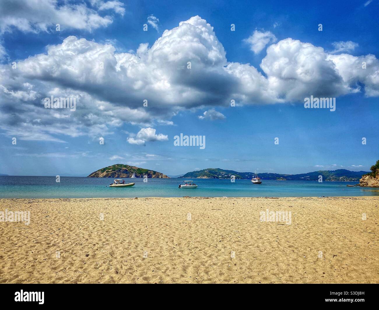 Sandy beach with boats and big clouds at uninhabited Tsougrias island near Skiathos, Greece. - Smartphone Captured Stock Image