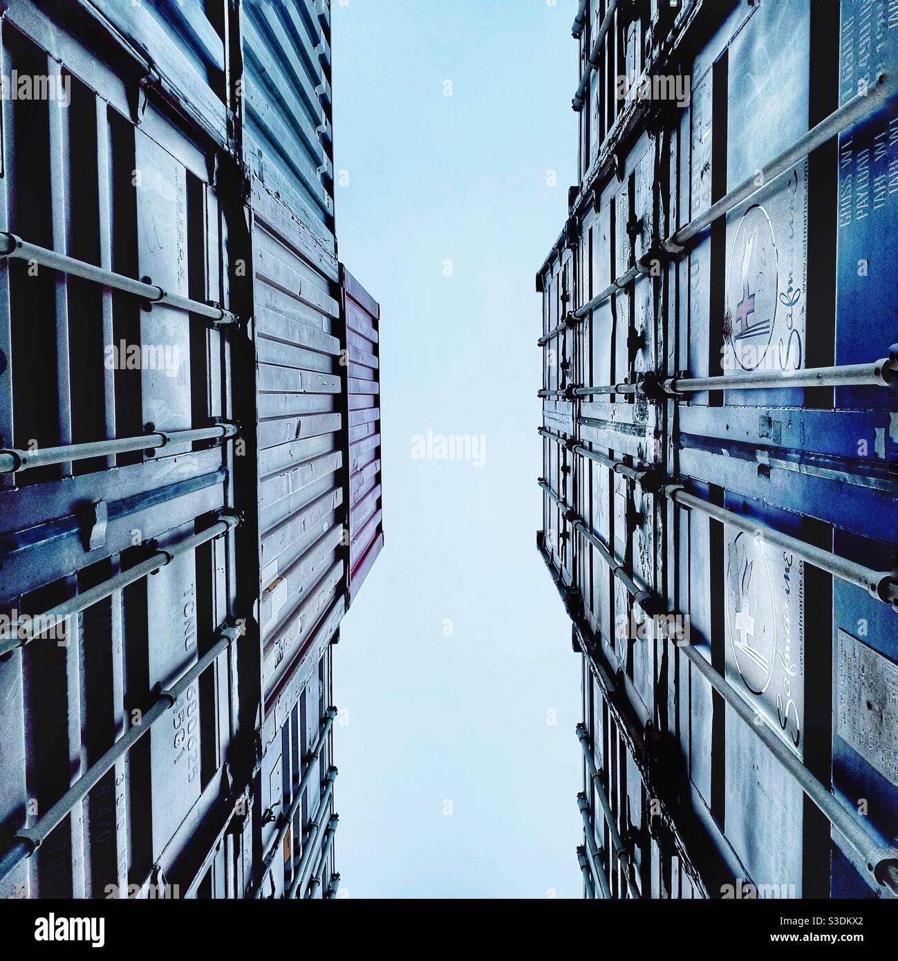 Looking up between stacked shipping containers to the sky in an industrial background with copy space - Smartphone Captured Stock Image