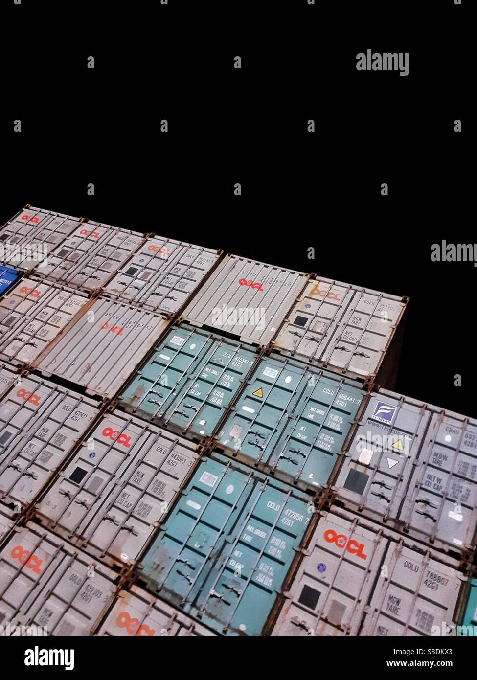 Stacked shipping containers or cargo boxes at night on a terminal or dock with copy space - Smartphone Captured Stock Image