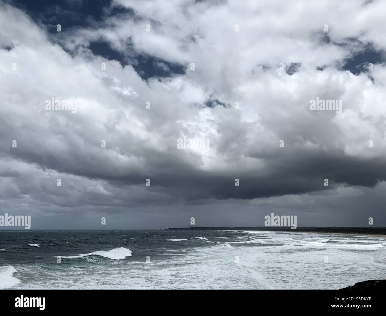 Stormy weather. Looming. Low down on the storm clouds over the frothy white ocean waves, NSW Australia Stock Photo