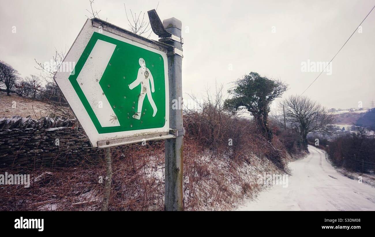 A photograph of an outdoor footpath sign in a rural country lane on a snowy day - Smartphone Captured Stock Image