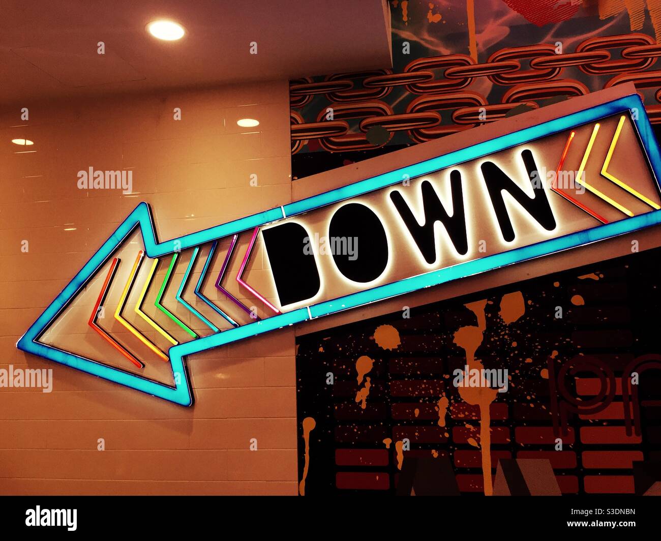 A large brightly lit down arrow points the way in an interior of a retail store, NYC, USA Stock Photo