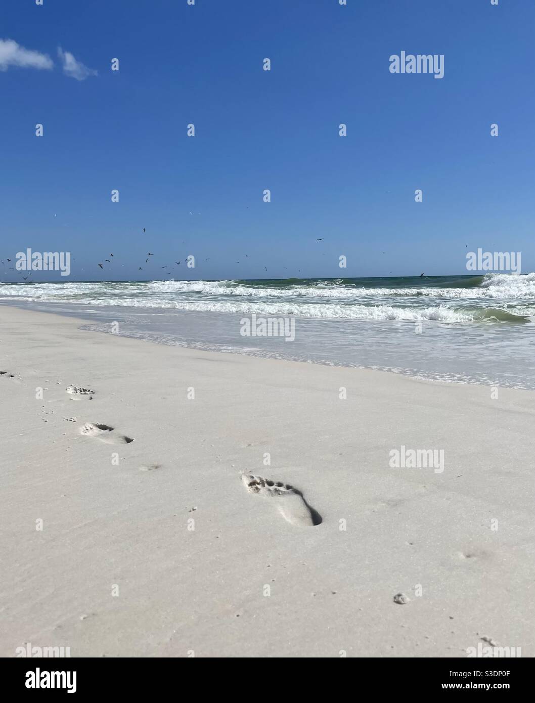 Footprints in the sand with large ocean waves - Smartphone Captured Stock Image