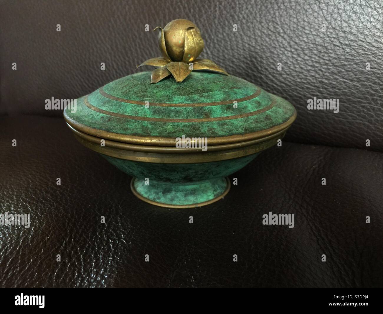 Covered ornate dish with metal rings against a plain background. - Smartphone Captured Stock Image