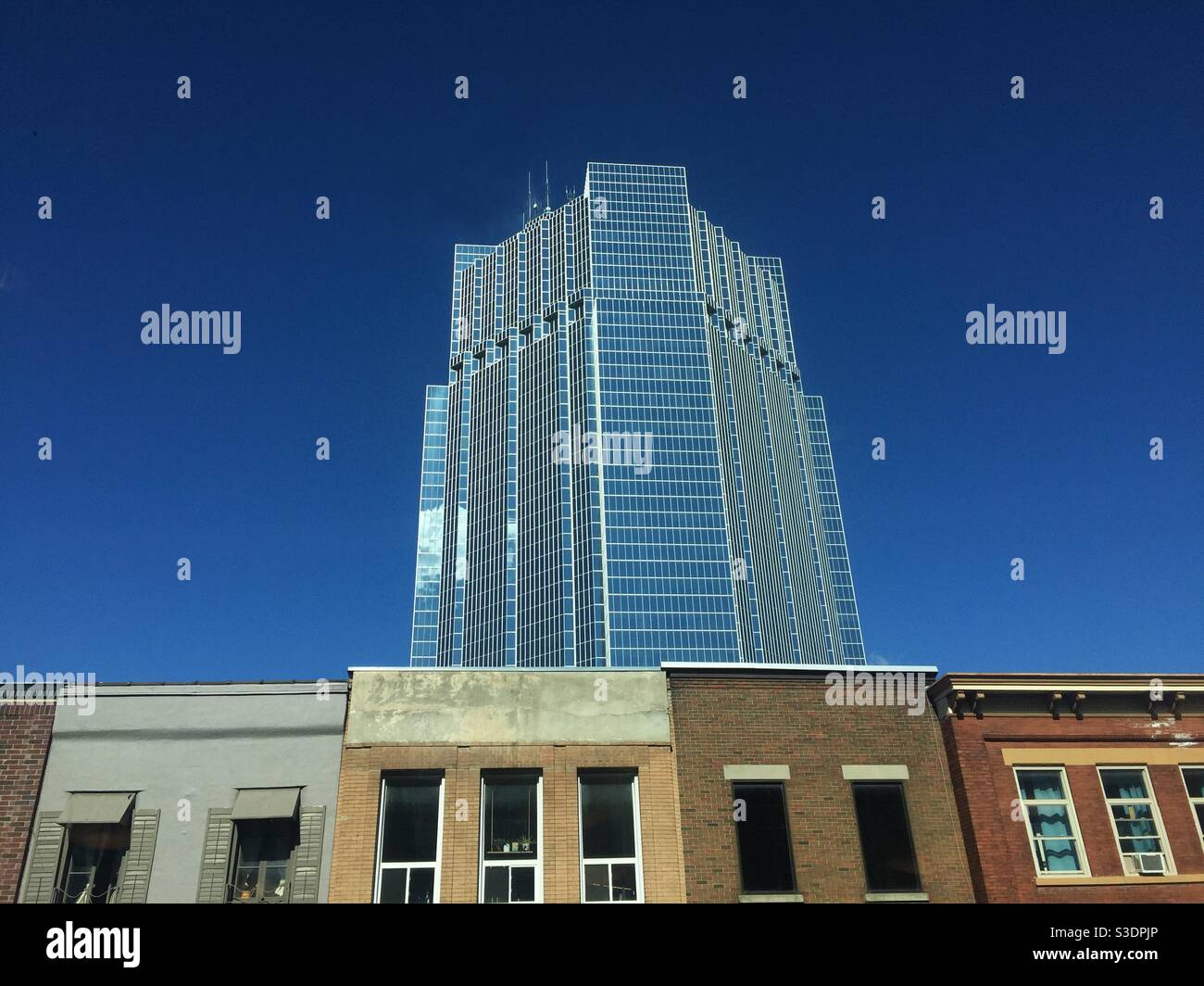Urban Streetscape, Ontario, Canada. An ultramodern tower rises above a row of traditional, low rise buildings on a blue sky day. Modern times. Stock Photo