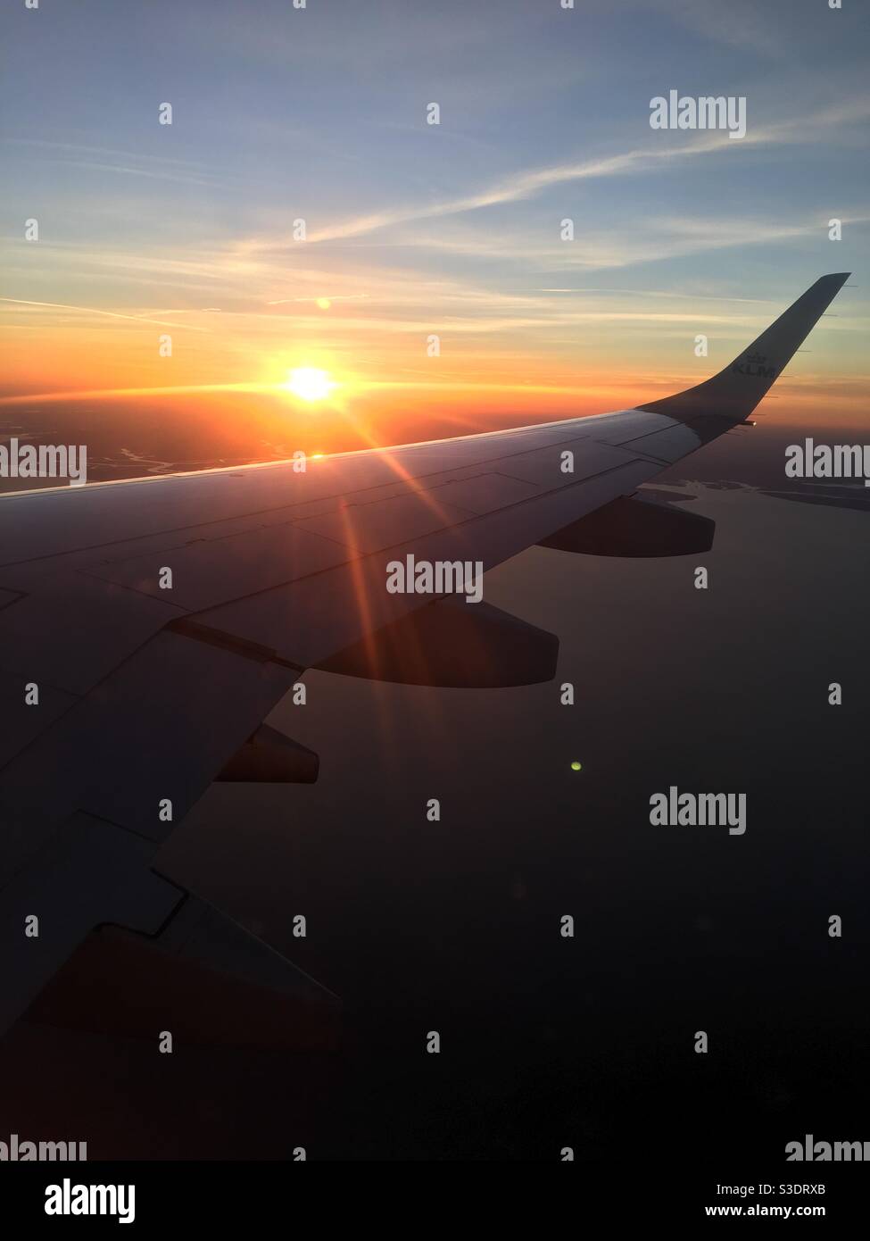 Plane sunset shot from the window of a passenger plane and showing the sun flare over the wing - Smartphone Captured Stock Image