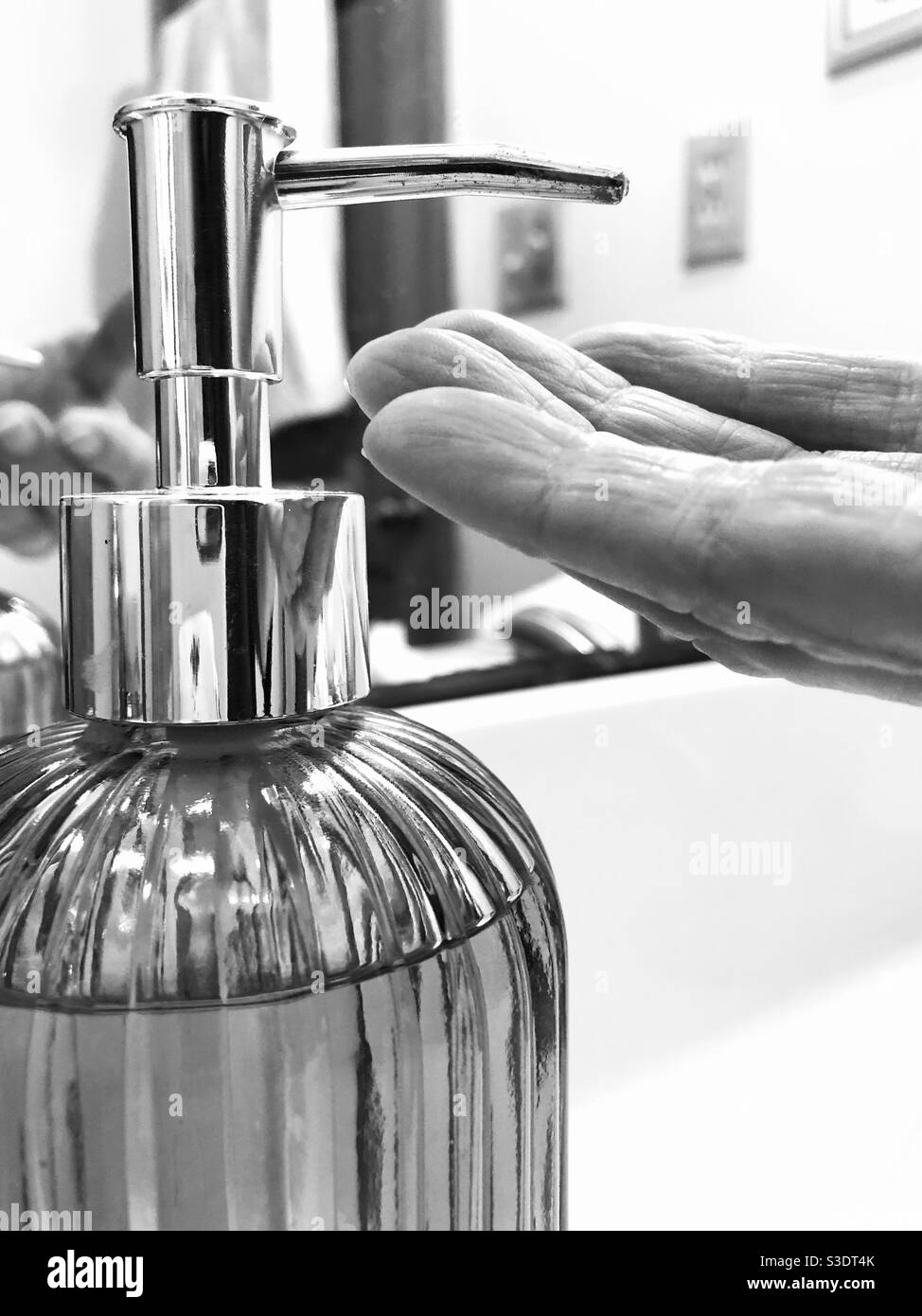 Hand and glass soap dispenser black and white - Smartphone Captured Stock Image