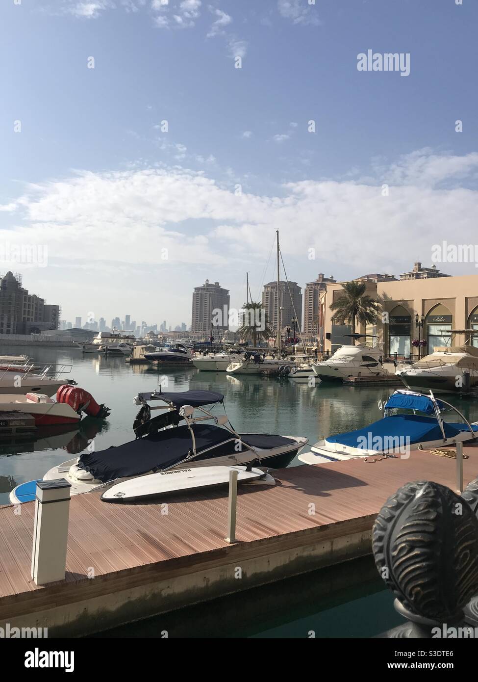 Porto Arabia on the artificial island of The Pearl in Doha, Qatar, with a view of the city skyline in the background - Smartphone Captured Stock Image