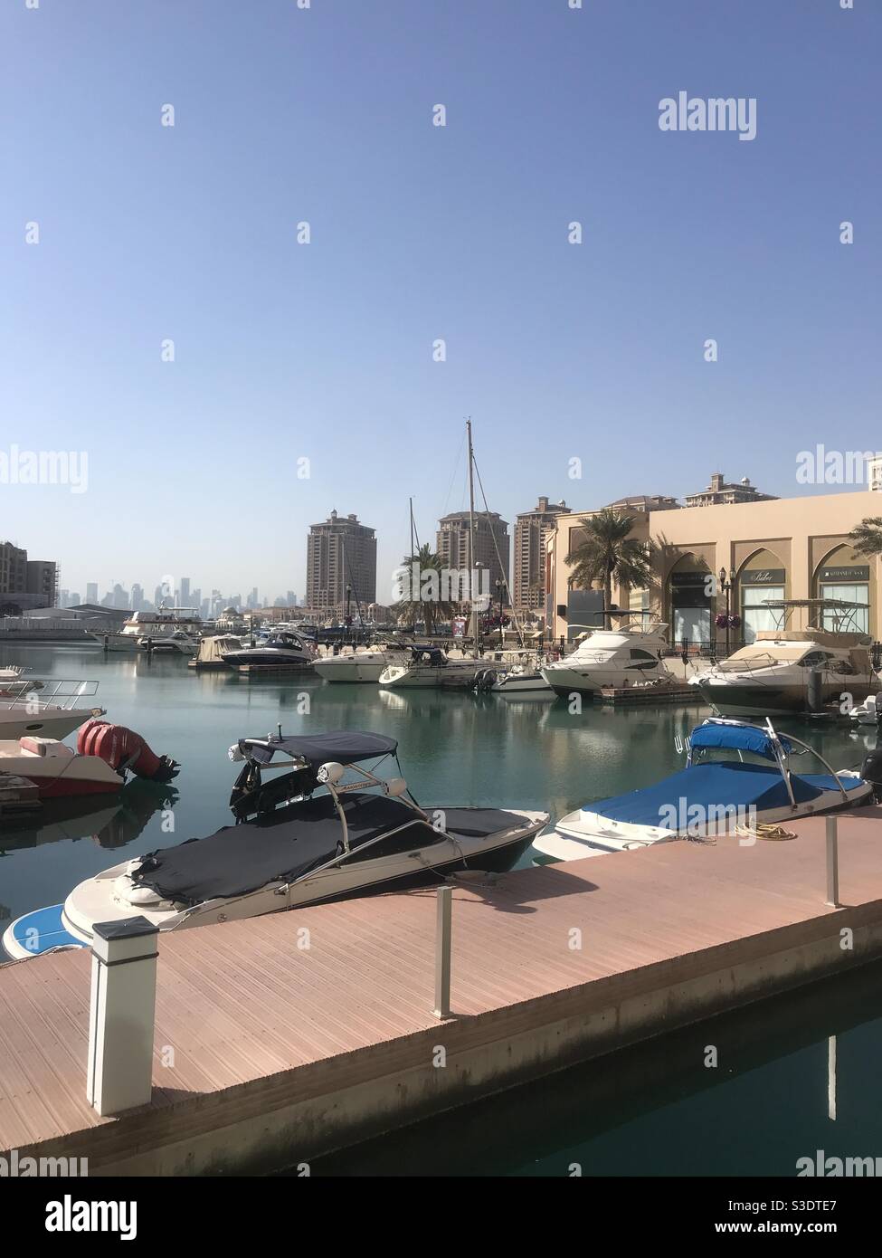 Porto Arabia on the artificial island of The Pearl in Doha, Qatar, with a view of the city skyline in the background - Smartphone Captured Stock Image