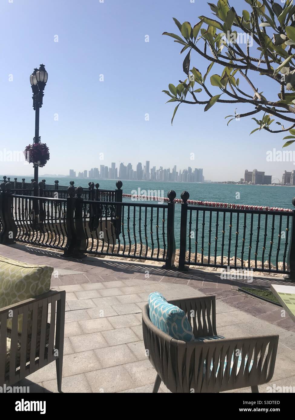 View taken from a restaurant terrace on Porto Arabia, The Pearl, with the city skyline in the background in Doha, Qatar - Smartphone Captured Stock Image