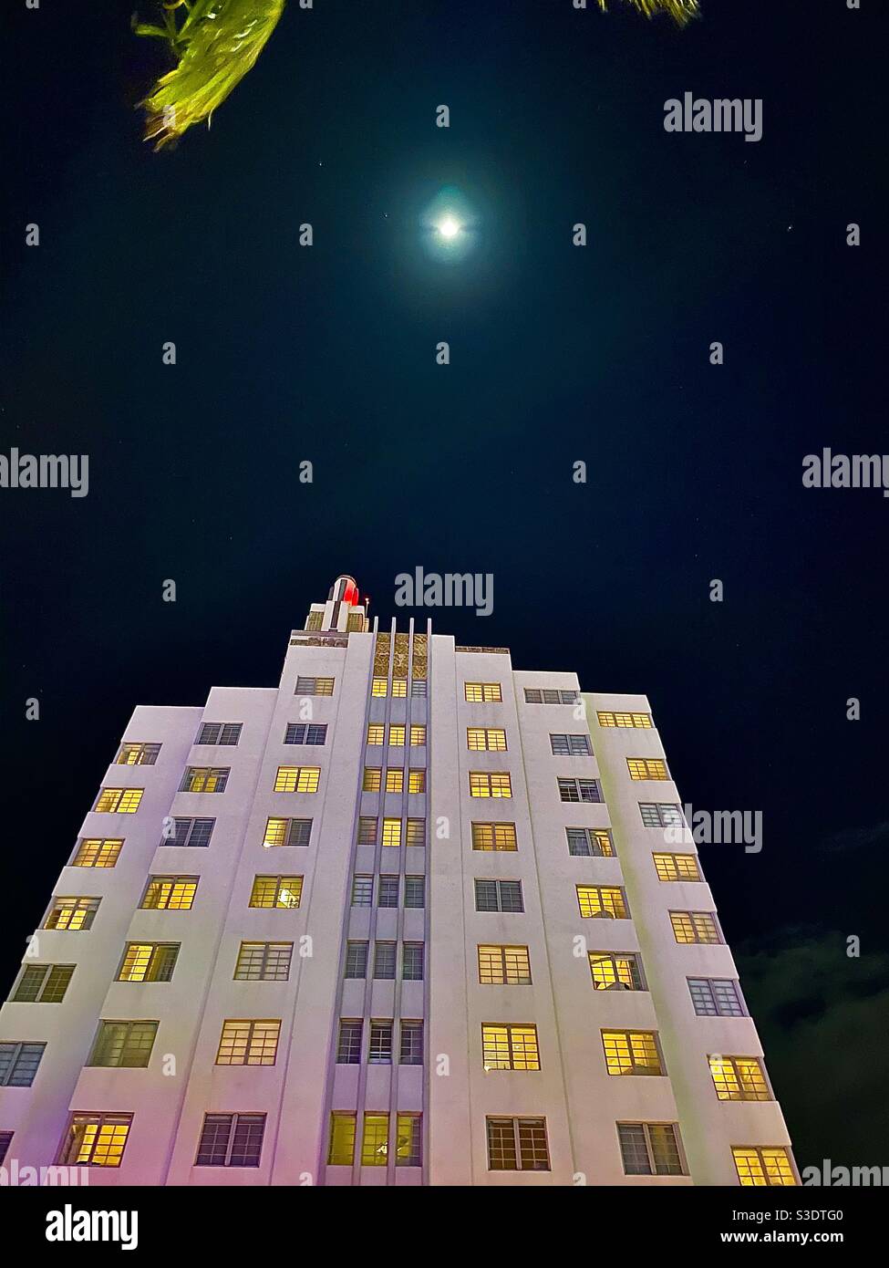 Looking upward at night at the towering trendy SLS hotel on popular Collins Avenue in South Miami Beach, Florida, USA under A full moon - Smartphone Captured Stock Image