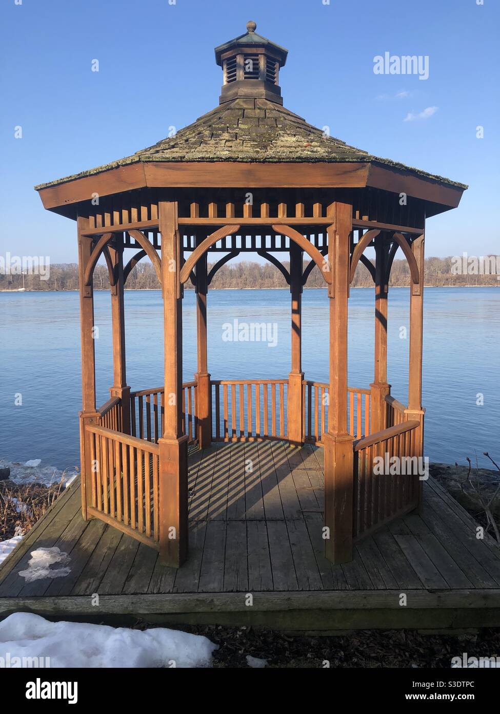 A wooden gazebo on the waters edge on a sunny winter day. - Smartphone Captured Stock Image