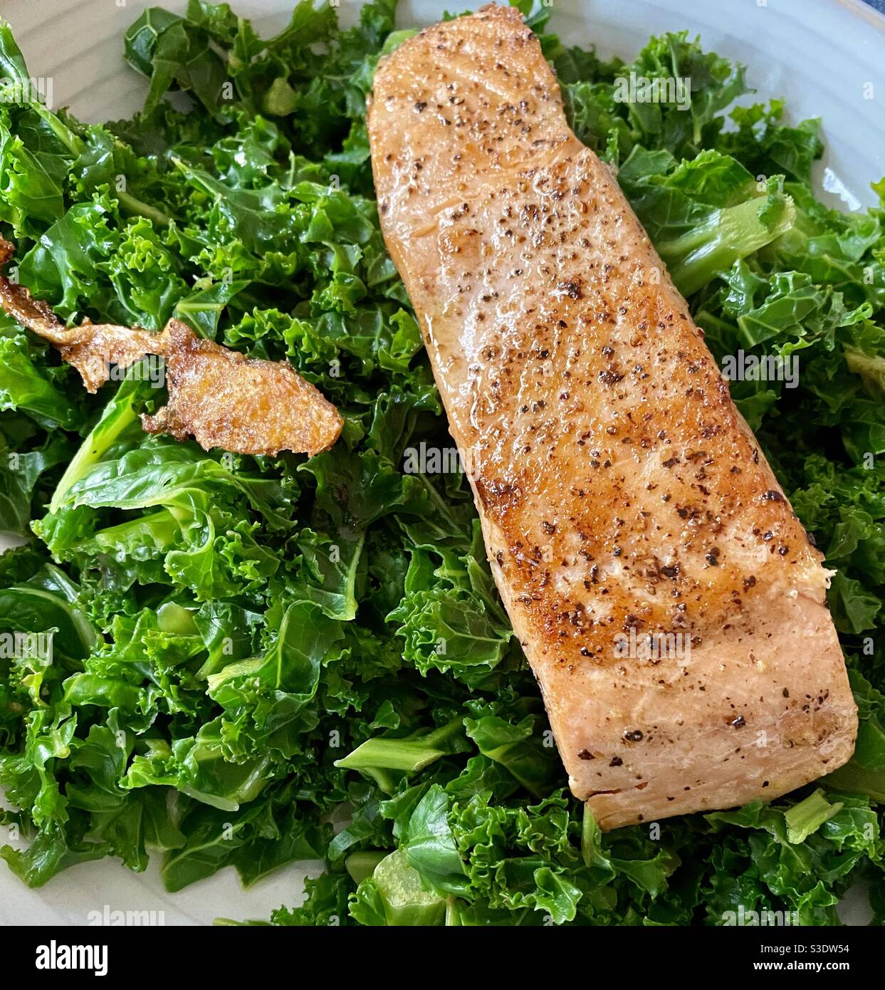 A juicy salmon fillet cooked to perfection on a bed of steamed Curly