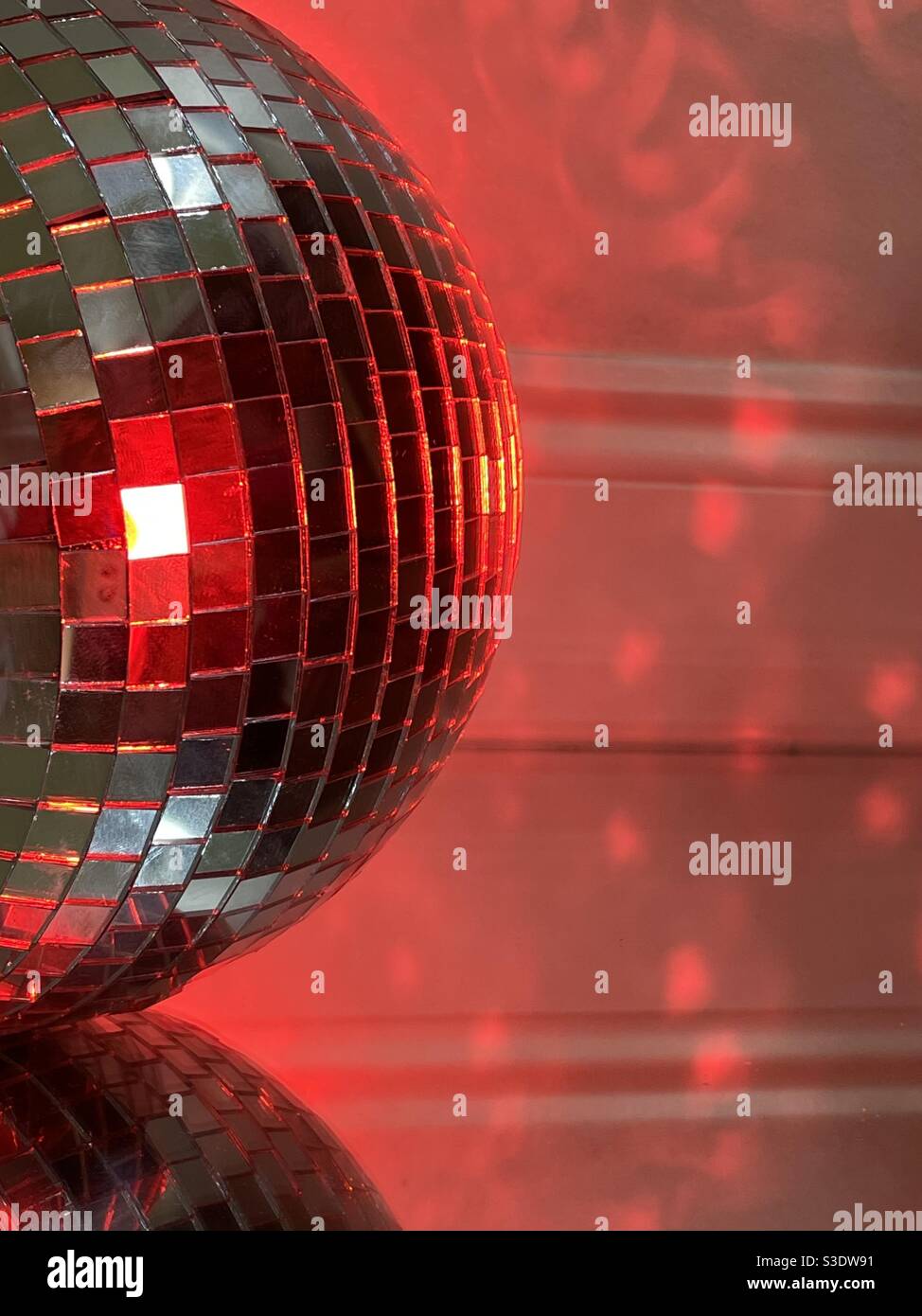 Disco ball with red lighting reflecting patterns on a wall - Smartphone Captured Stock Image