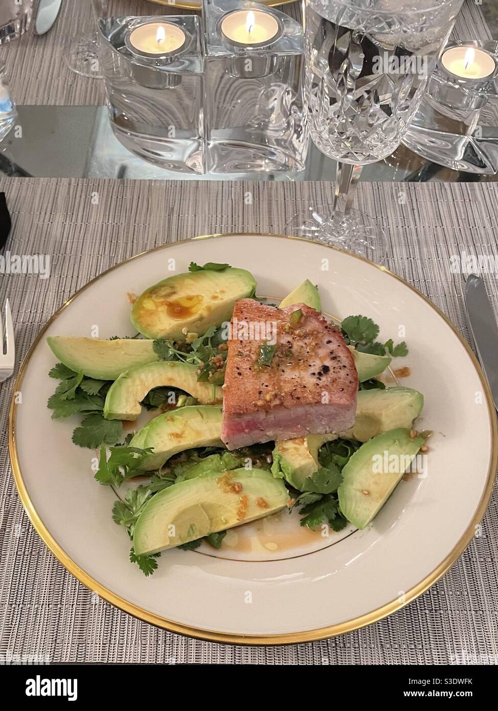 Elegant meal of seared tuna with avocado on cilantro on a gold-trimmed china plate. - Smartphone Captured Stock Image