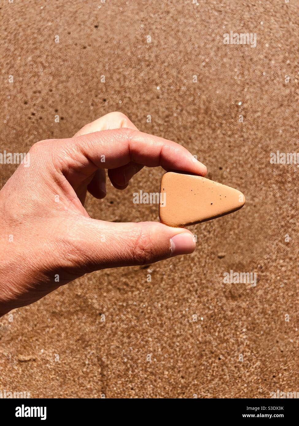 Hand of a person holding a rock that looks like a play button icon Stock Photo