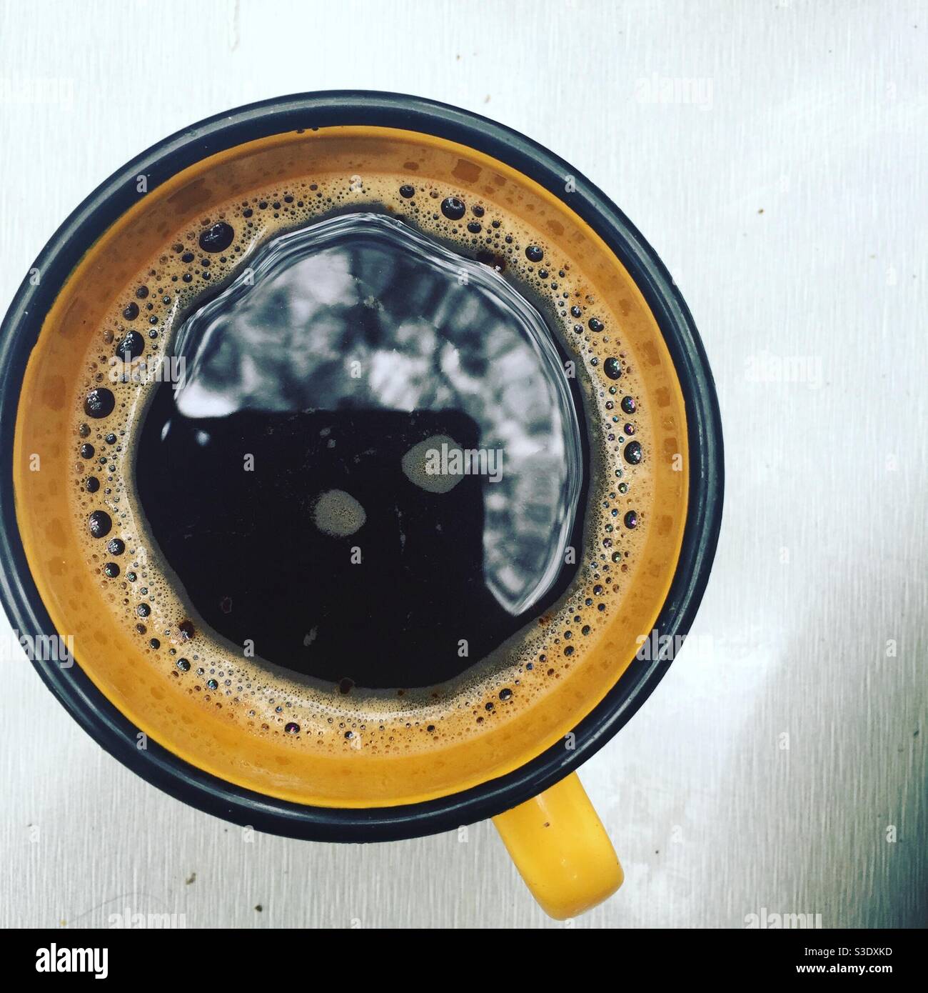 https://c8.alamy.com/comp/S3DXKD/cup-of-black-coffee-in-yellow-enamel-mug-coffee-cup-with-reflection-of-trees-while-camping-S3DXKD.jpg