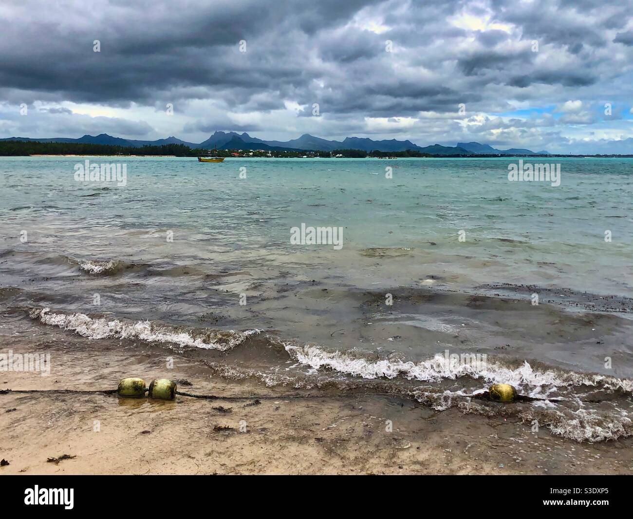 Brown waters with white buoys and seaweed brought by the storm on the public beach in Mont Choisy, Mauritius. - Smartphone Captured Stock Image