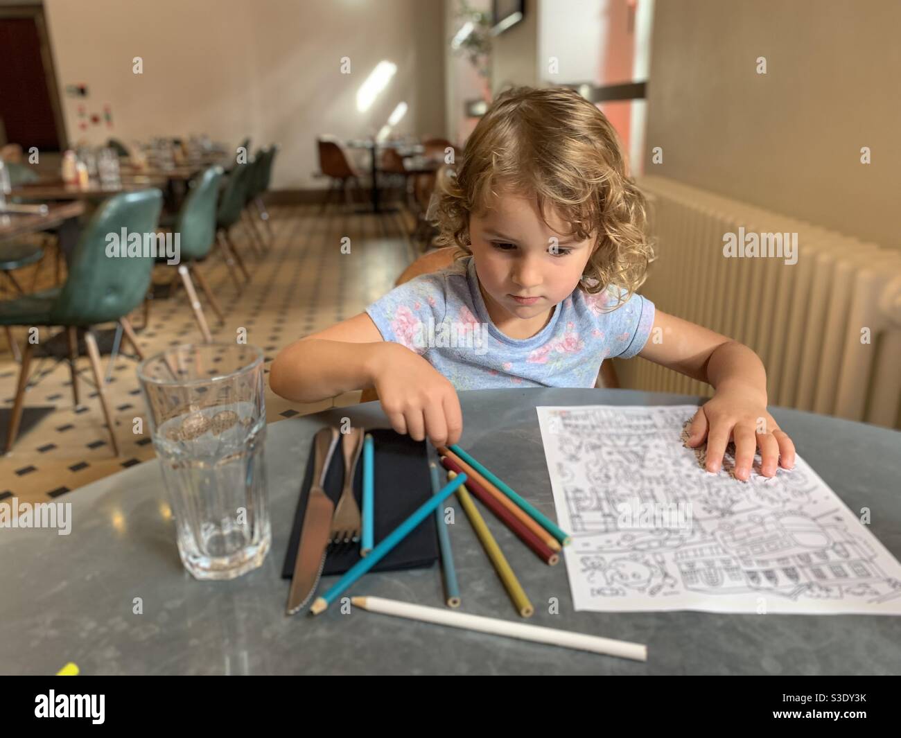 Little girl colouring in a restaurant Stock Photo