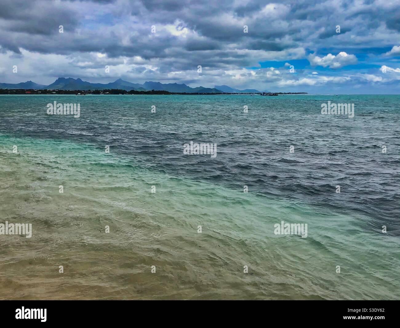 Wavy sea with mountains in the background, Mauritius. - Smartphone Captured Stock Image