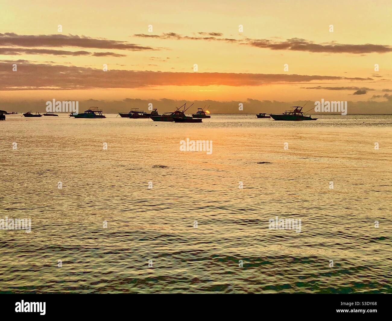 Yellow sunset with boat silhouettes in Mauritius. - Smartphone Captured Stock Image