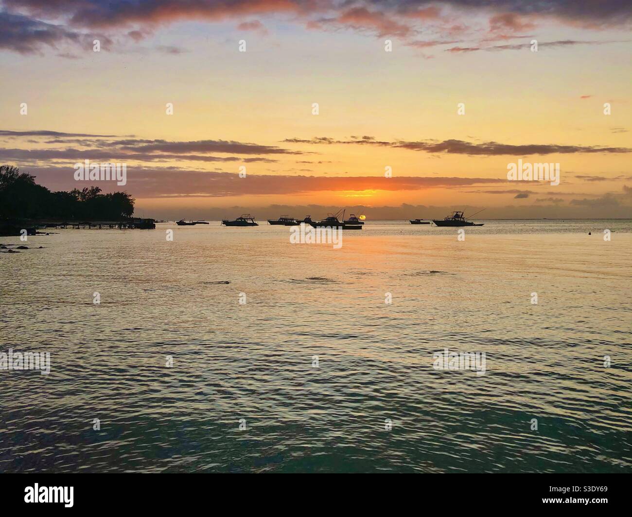 Yellow sunset with sea boat silhouettes in Mauritius. - Smartphone Captured Stock Image