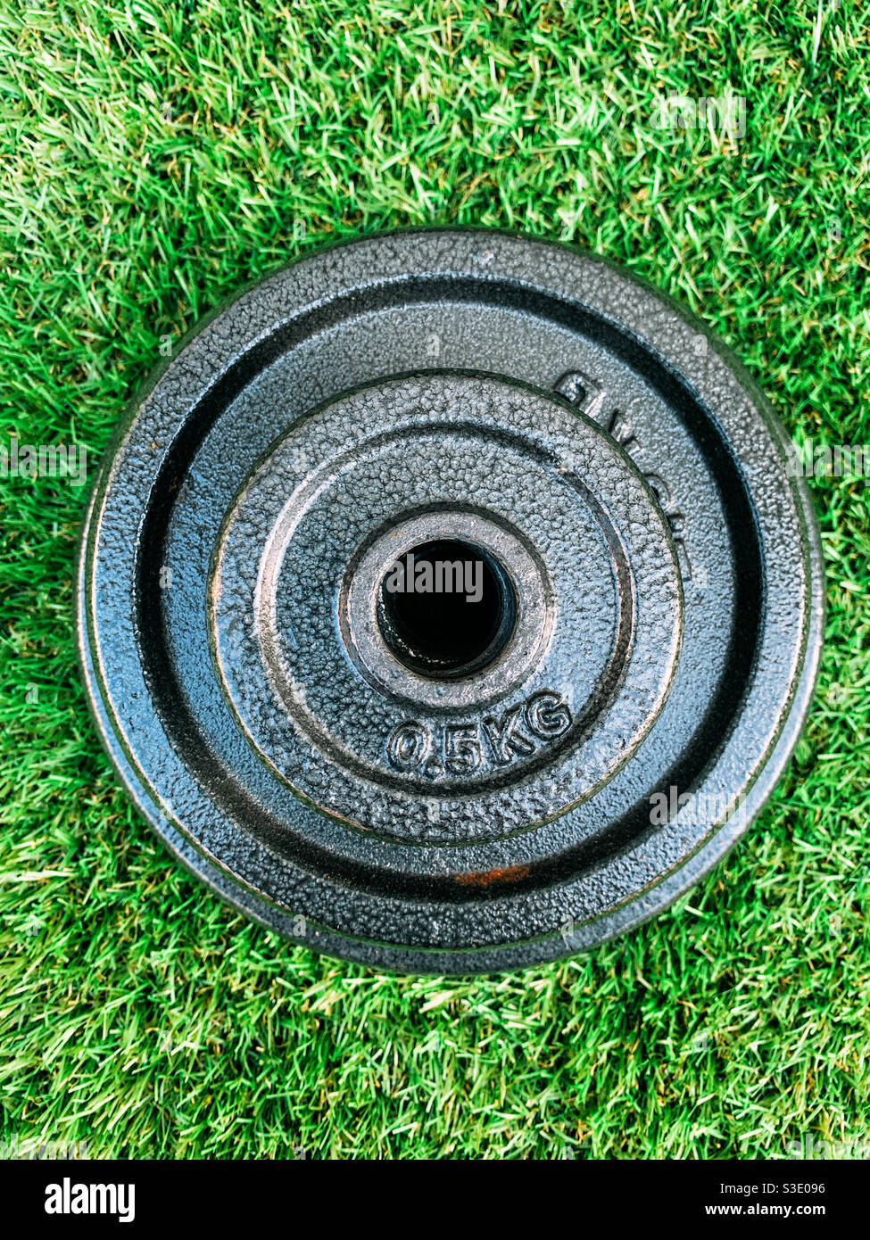 Top view of a set of dumbbells weight plates on artificial grass - Smartphone Captured Stock Image
