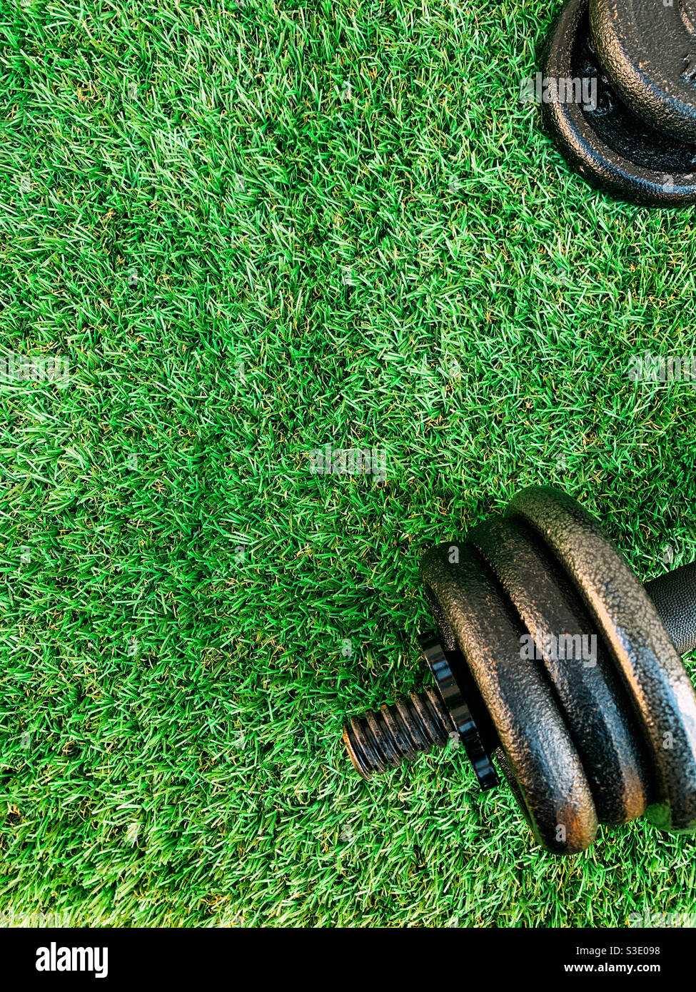 Top view of a dumbbells and weight plates on artificial grass - Smartphone Captured Stock Image