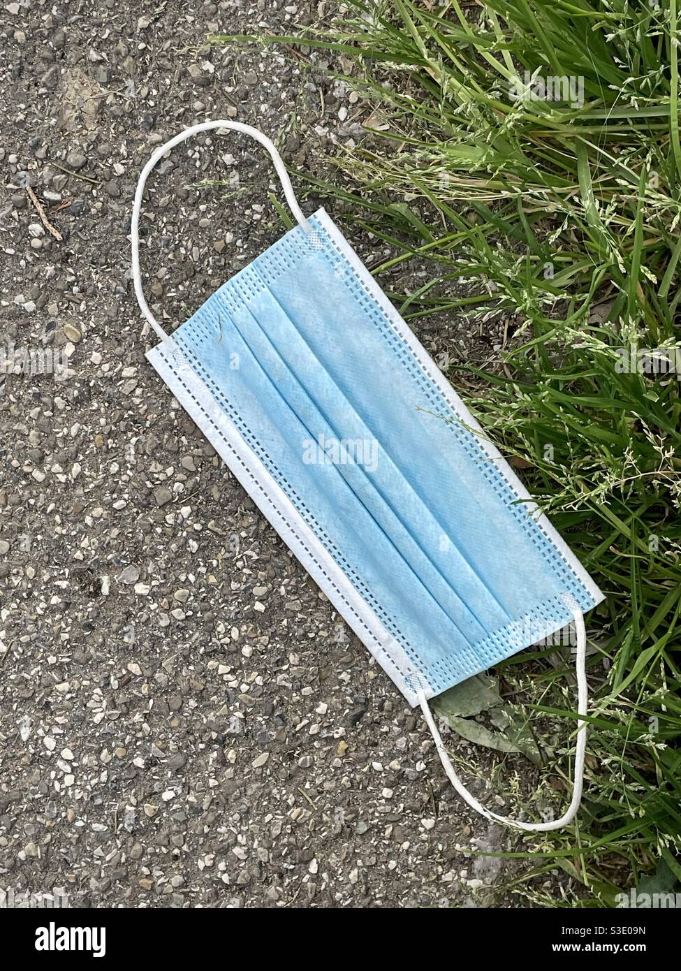 Face mask left on the pavement off a street in Italy Stock Photo