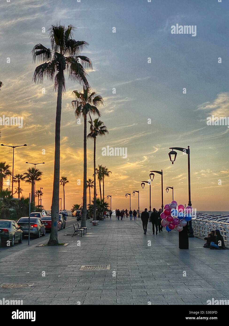 Lovely Beirut - Lebanon promenade at sunset with people walking by the sea and a lady selling colored balloons Stock Photo