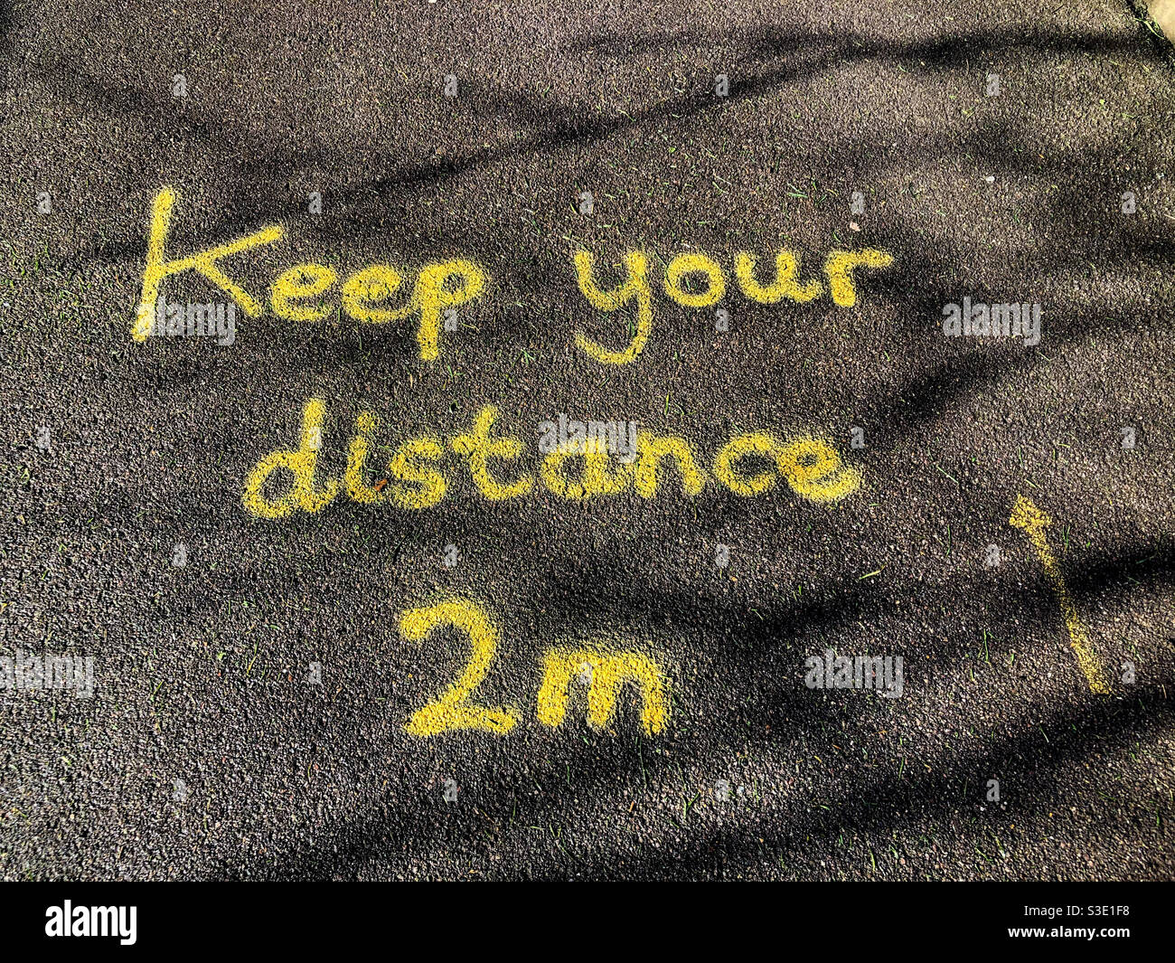Social distancing instructions painted in the floor in yellow paint at the entrance to a school. - Smartphone Captured Stock Image