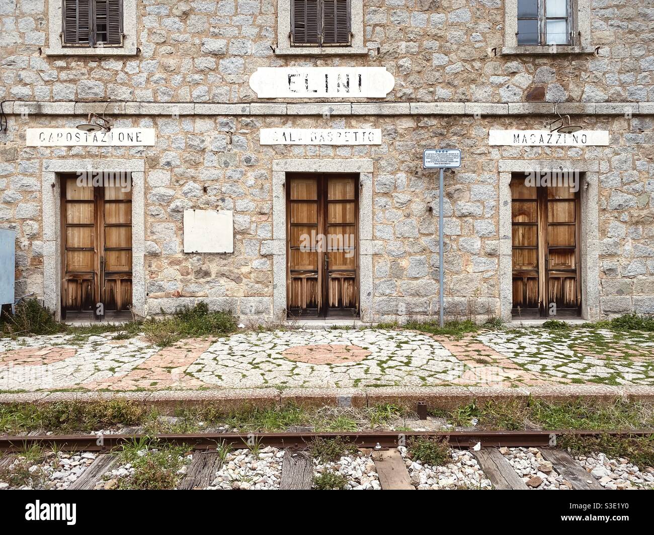 Frontal view of an old, dismissed and abandoned train station with signs written in Italian. Stock Photo