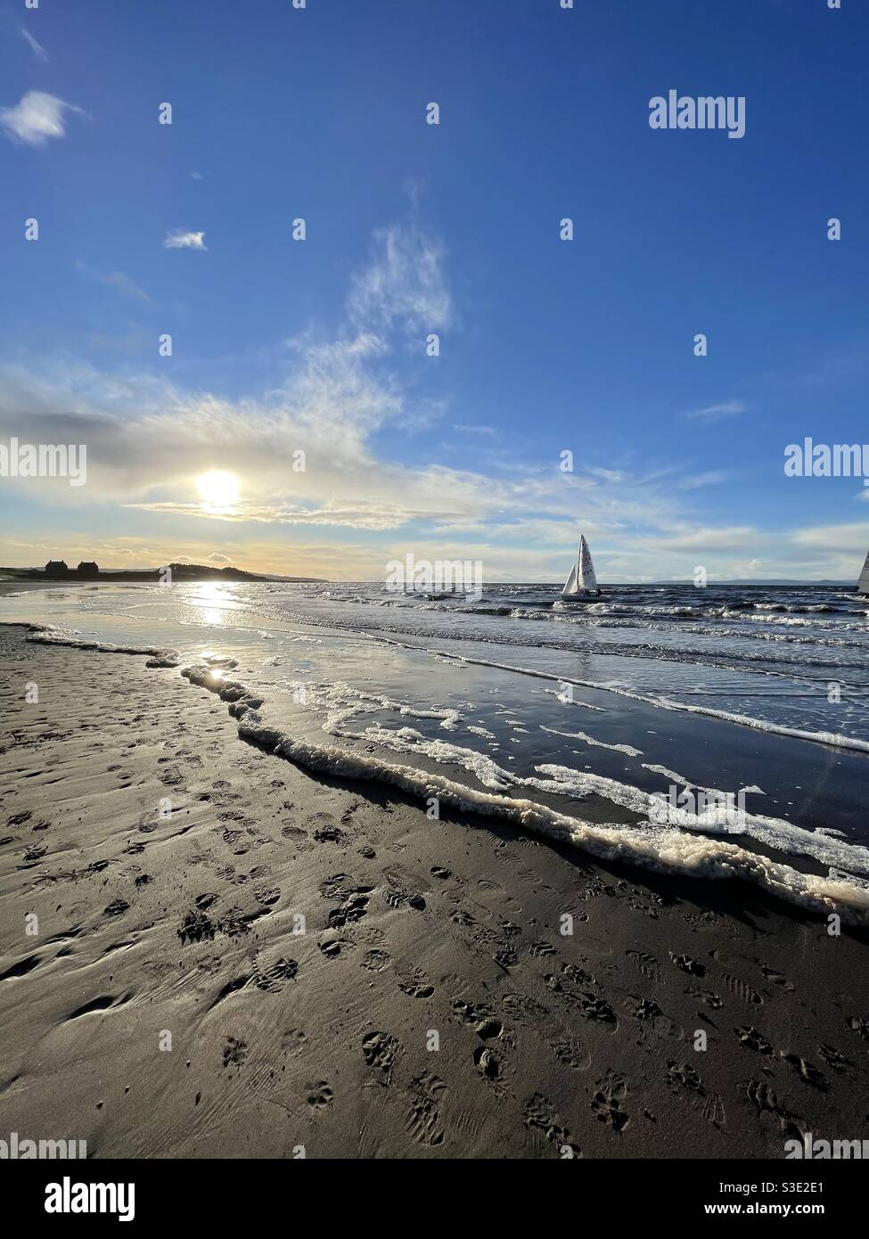 Beautiful Scenic view of sunset over ocean from Prestwick beach, Ayrshire, Scotland on Firth of Clyde, west coast with a single yacht in the sea. - Smartphone Captured Stock Image