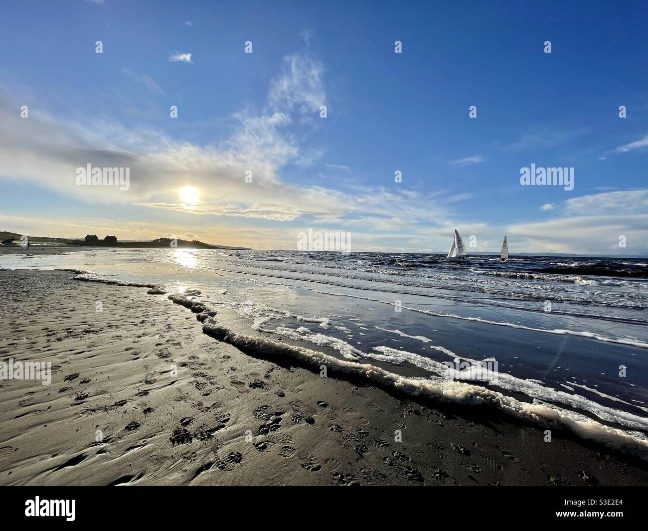 Beautiful Scenic view of sunset over ocean from Prestwick beach, Ayrshire, Scotland on Firth of Clyde, west coast with two yachts sailing in the sea. - Smartphone Captured Stock Image