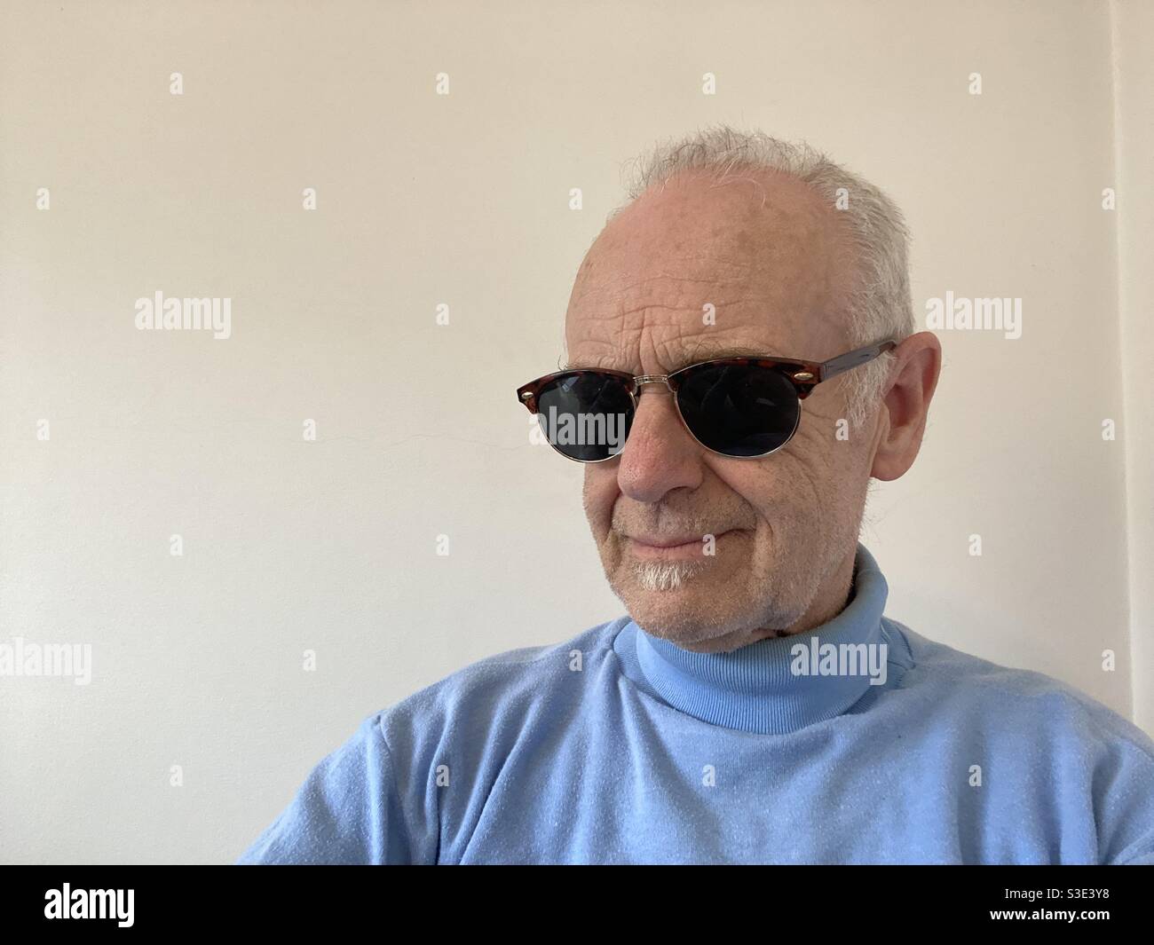 March 2021 - Mature guy in a blue top and classic retro sun glasses - Smartphone Captured Stock Image