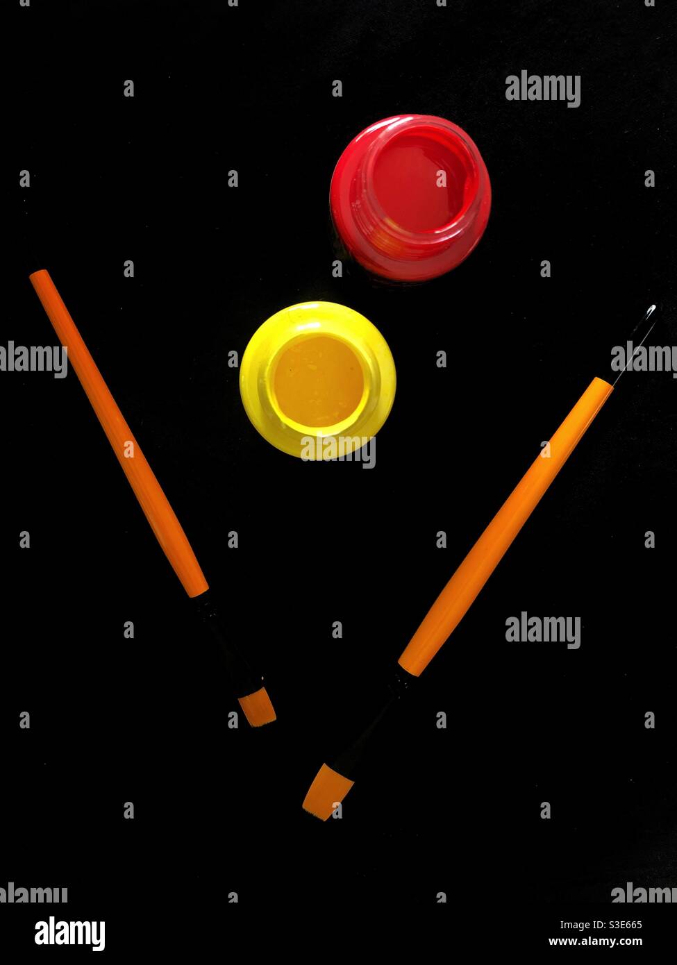 Two paint brushes and red and yellow paint photographed from top view - Smartphone Captured Stock Image