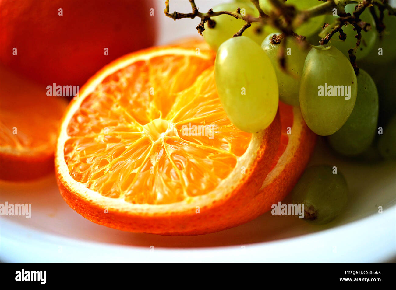 A bunch of white grapes and sliced oranges on a plate - Smartphone Captured Stock Image