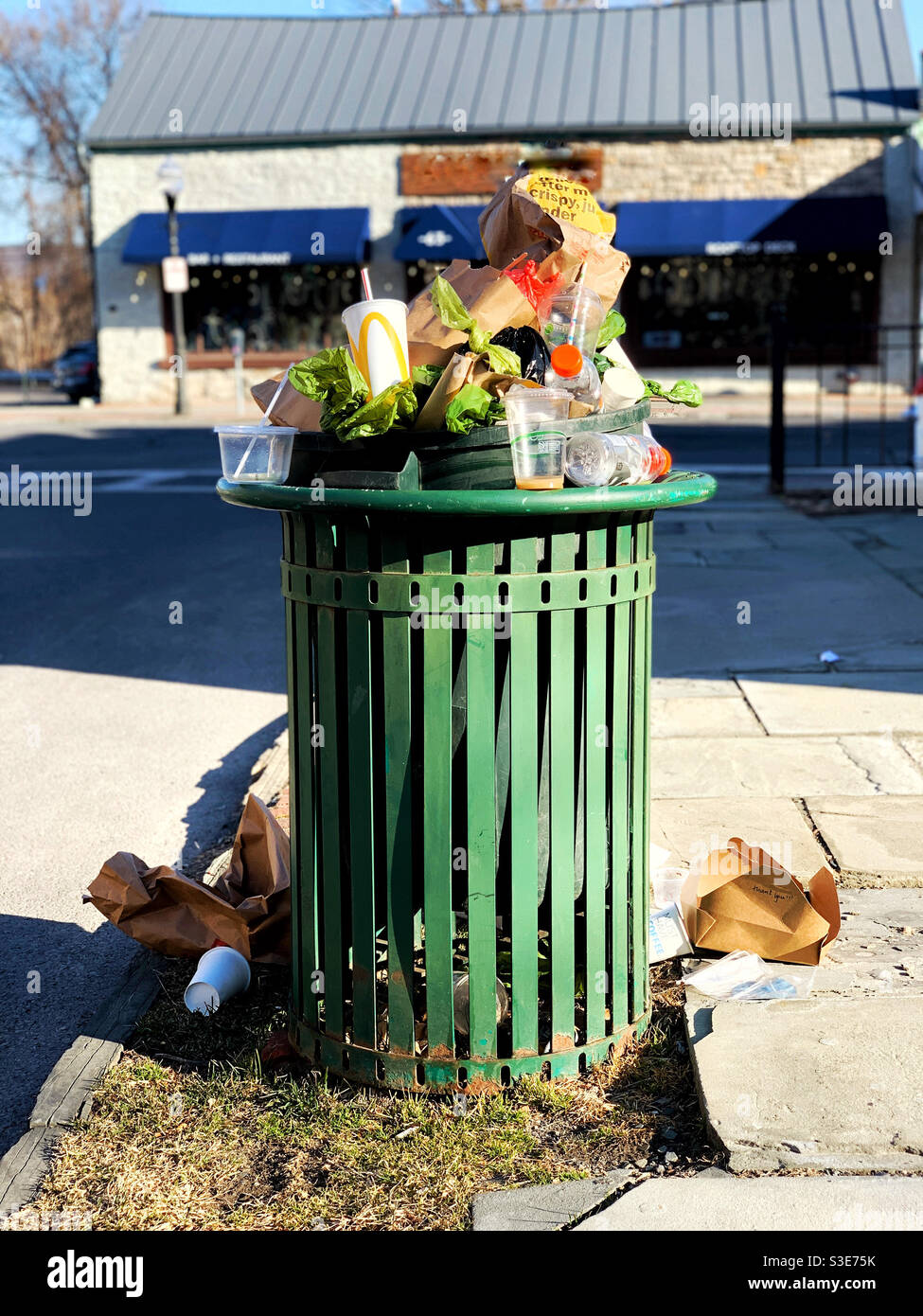 Trash can overflow with take out and fast food garbage by park in city - Smartphone Captured Stock Image