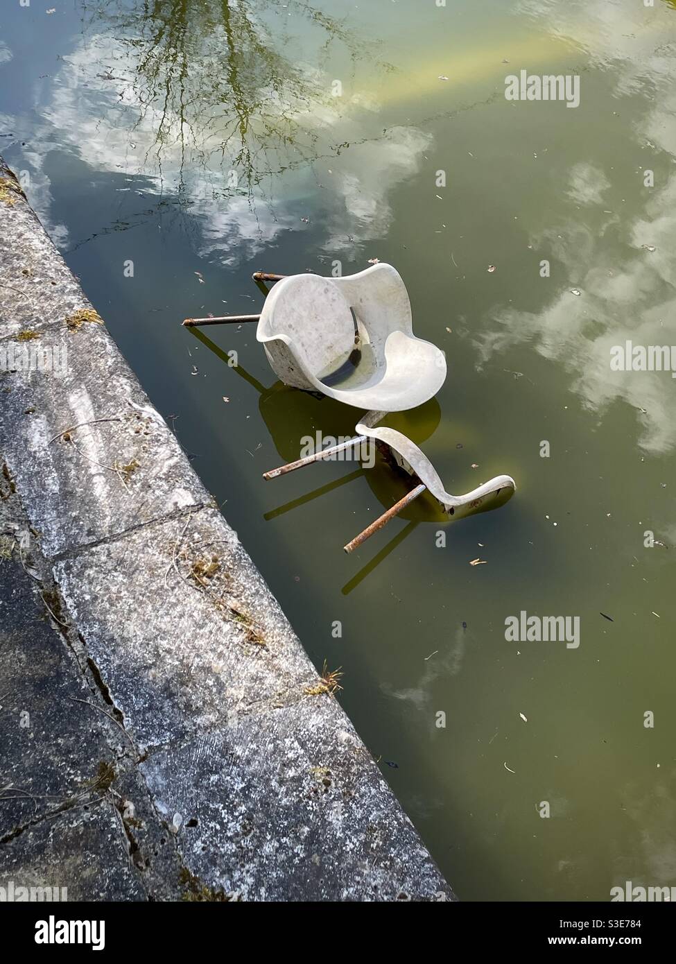 Two chairs abandoned in the water off an old swimming pool Stock Photo
