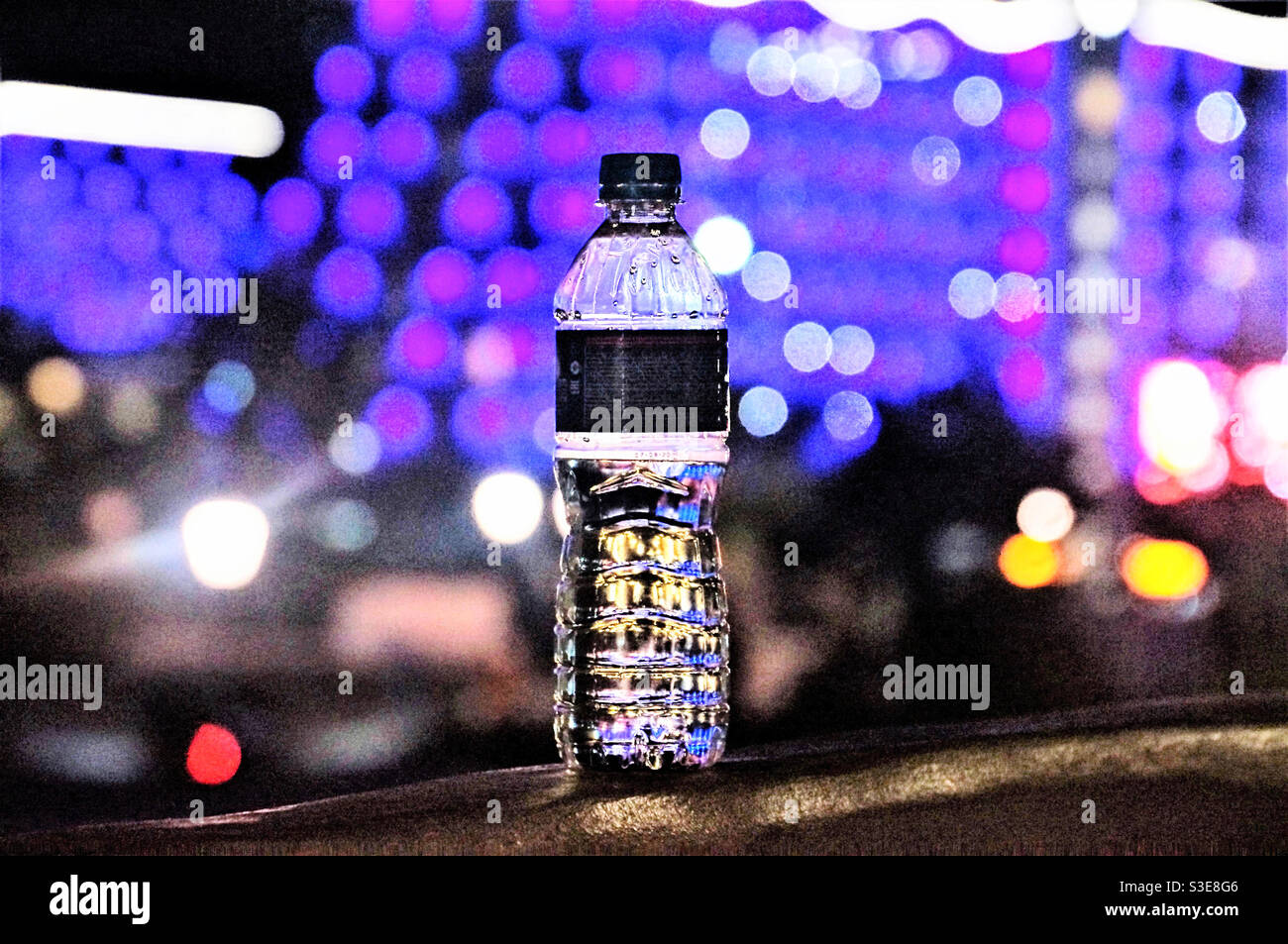 A bottle of water on a background of evening colored lights - Smartphone Captured Stock Image