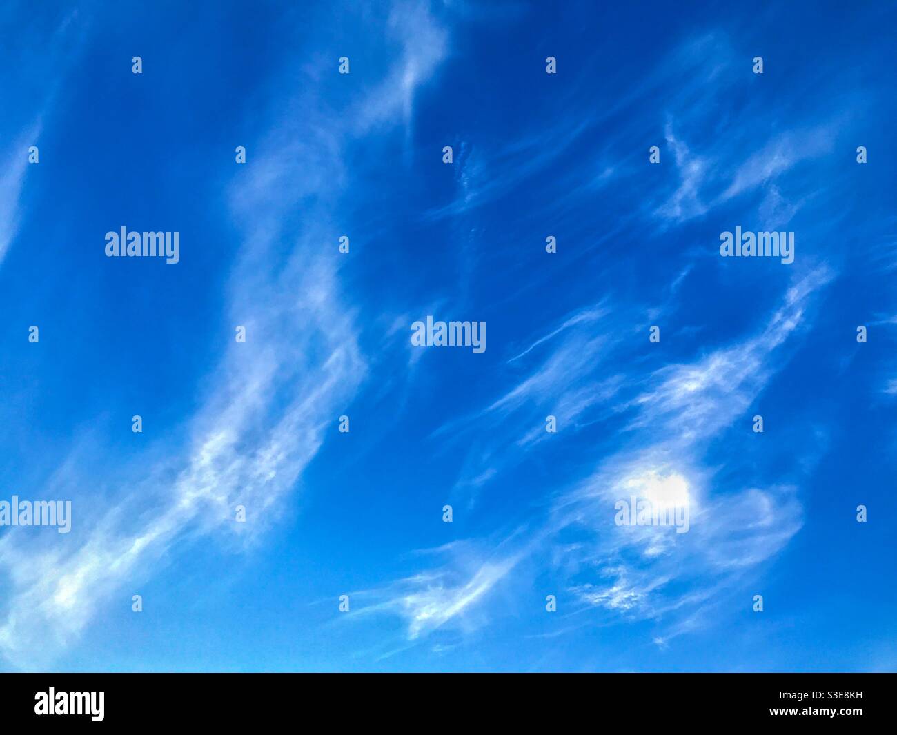 Deep blue sky with wisps of white cloud. Background. Stock Photo