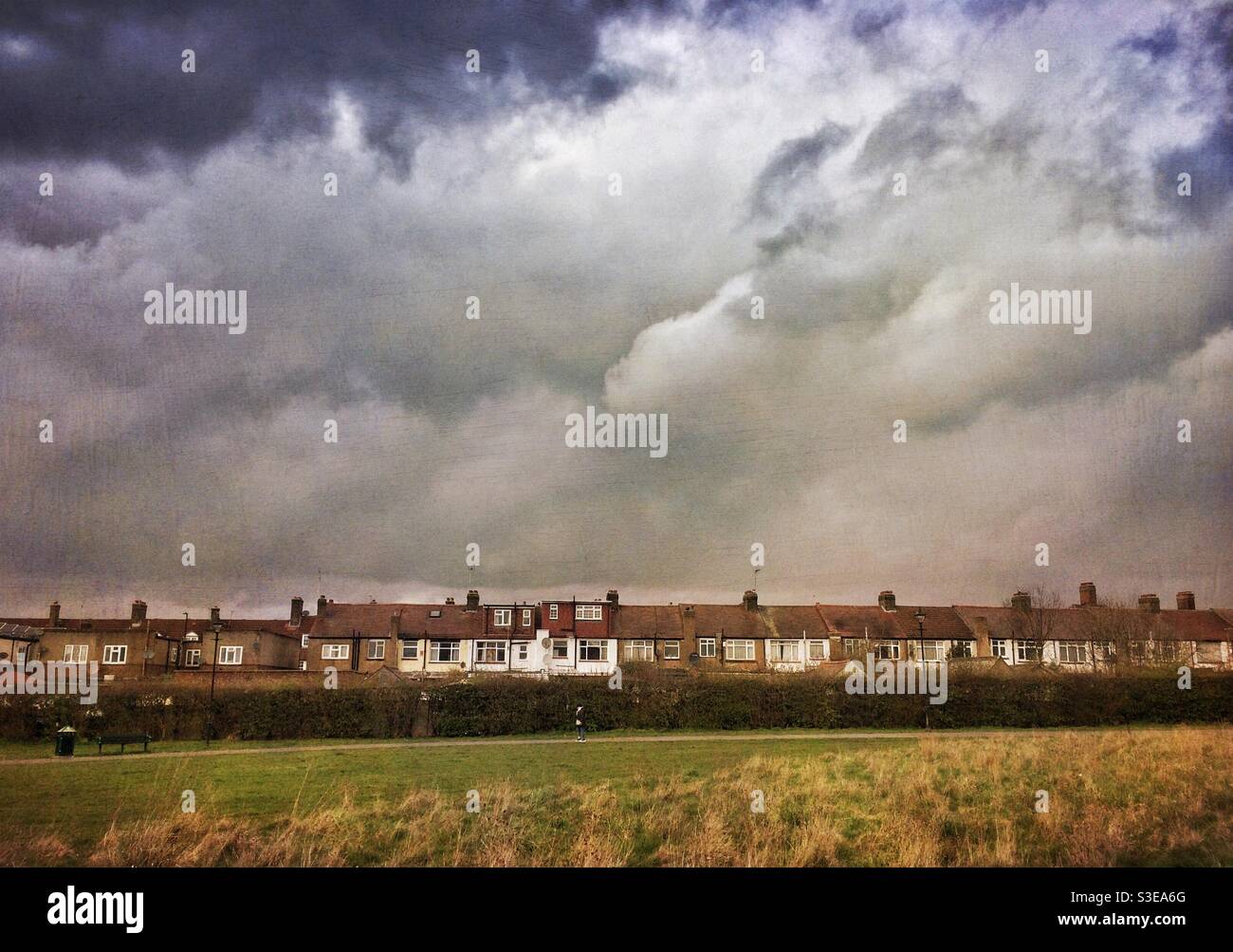 A row of terraced houses beneath a dramatic sky as seen from a park - Smartphone Captured Stock Image