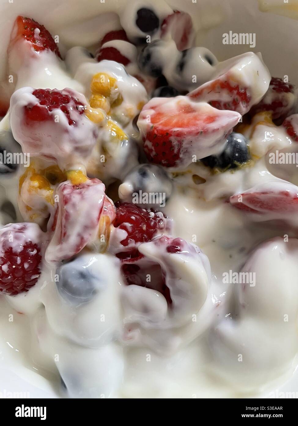 Raspberries, blueberries, strawberries and passionfruit with plain yoghurt in a china bowl - Smartphone Captured Stock Image