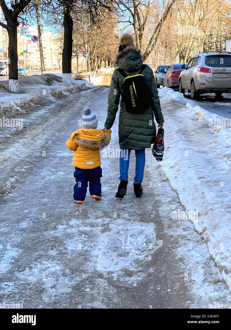 A young woman by the hand leads a child along a slippery path Stock ...