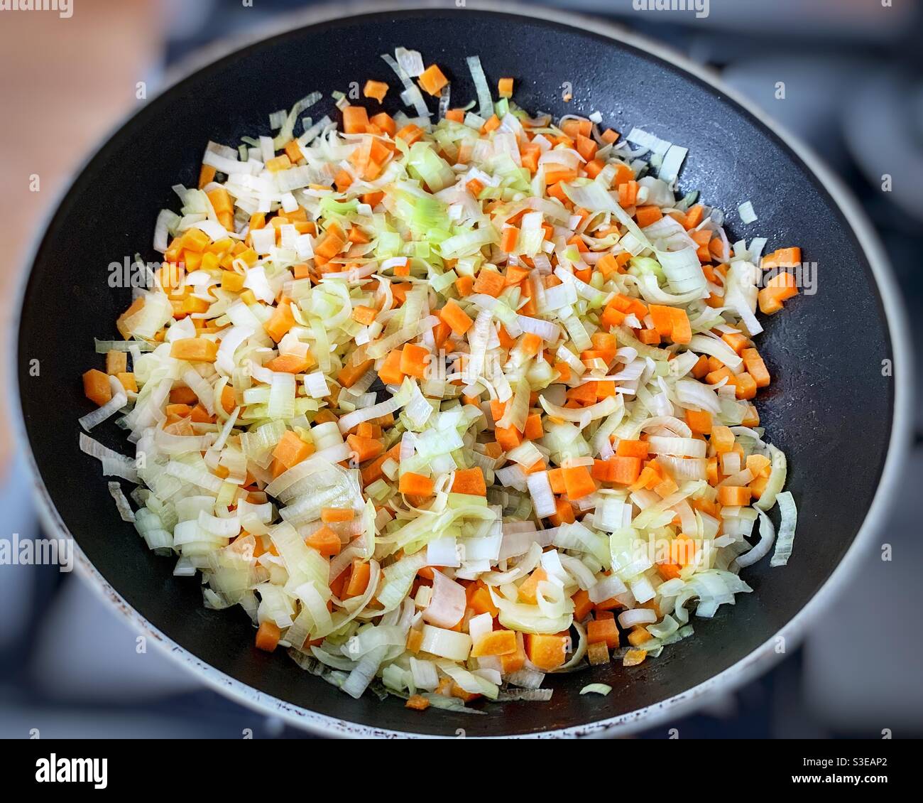 Diced carrots and sliced leeks cooking in olive oil in a frying pan. - Smartphone Captured Stock Image