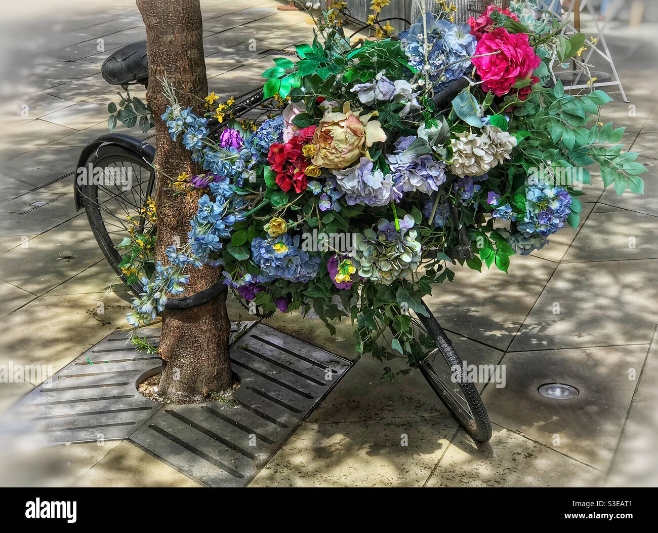 Bicycle covered in large flower arrangement. Stock Photo