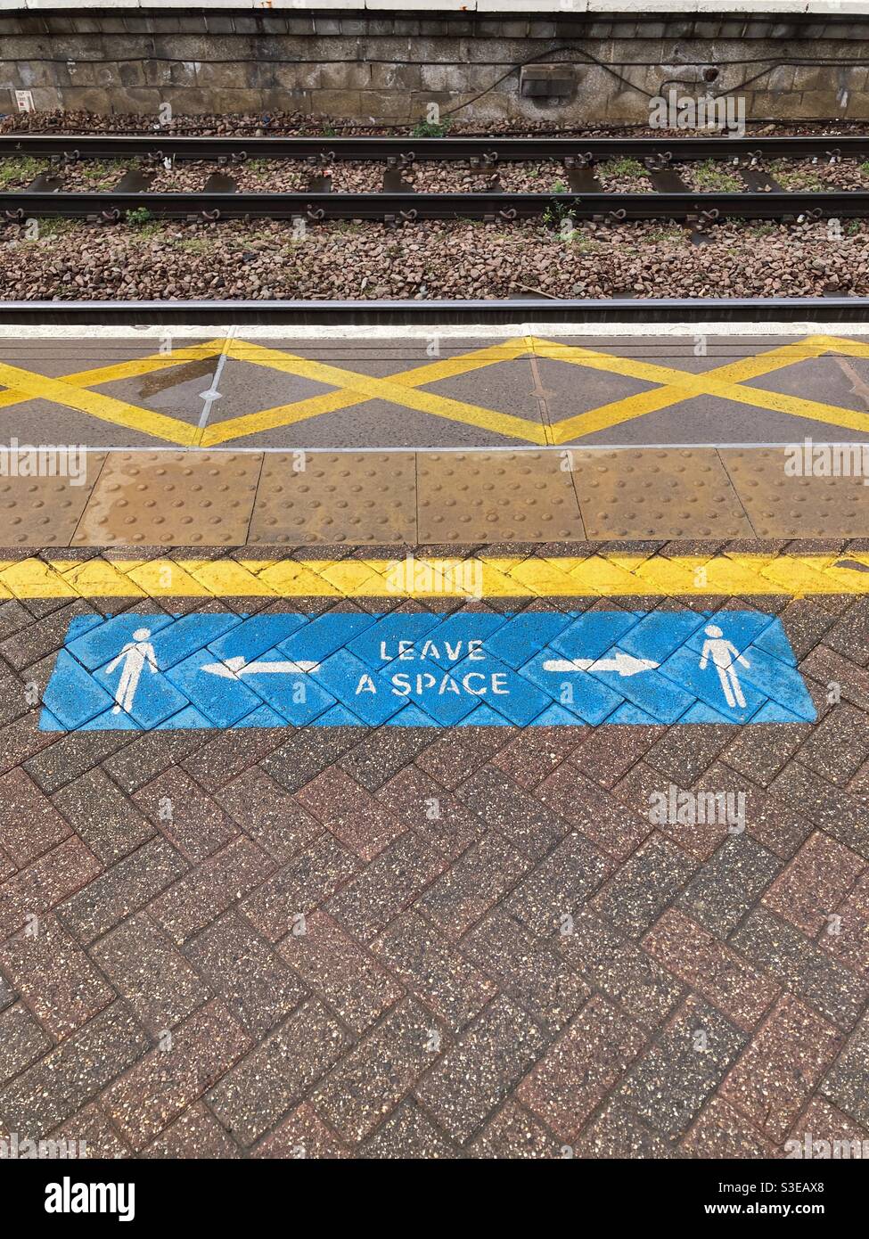 Train platform with signage saying ‘leave a space’ - Smartphone Captured Stock Image